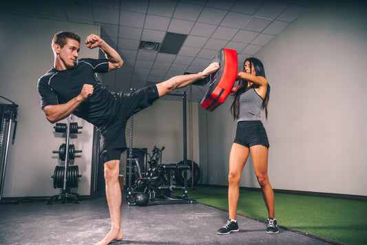 En mann og en kvinne som øver på kickboksing